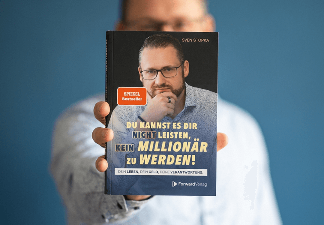 Sven Stopka hält sein Finanzbuch „Du kannst es dir nicht leisten, kein Millionär zu werden“ in die Kamera