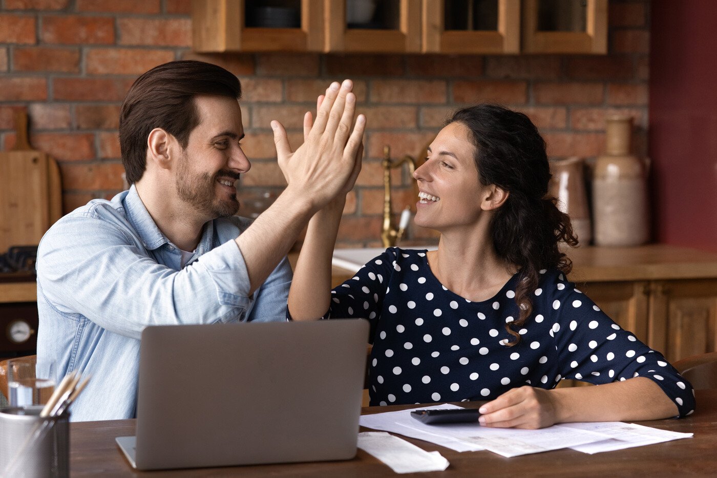 Glückliches Paar gibt sich nach der Berechnung seiner Finanzen High Five